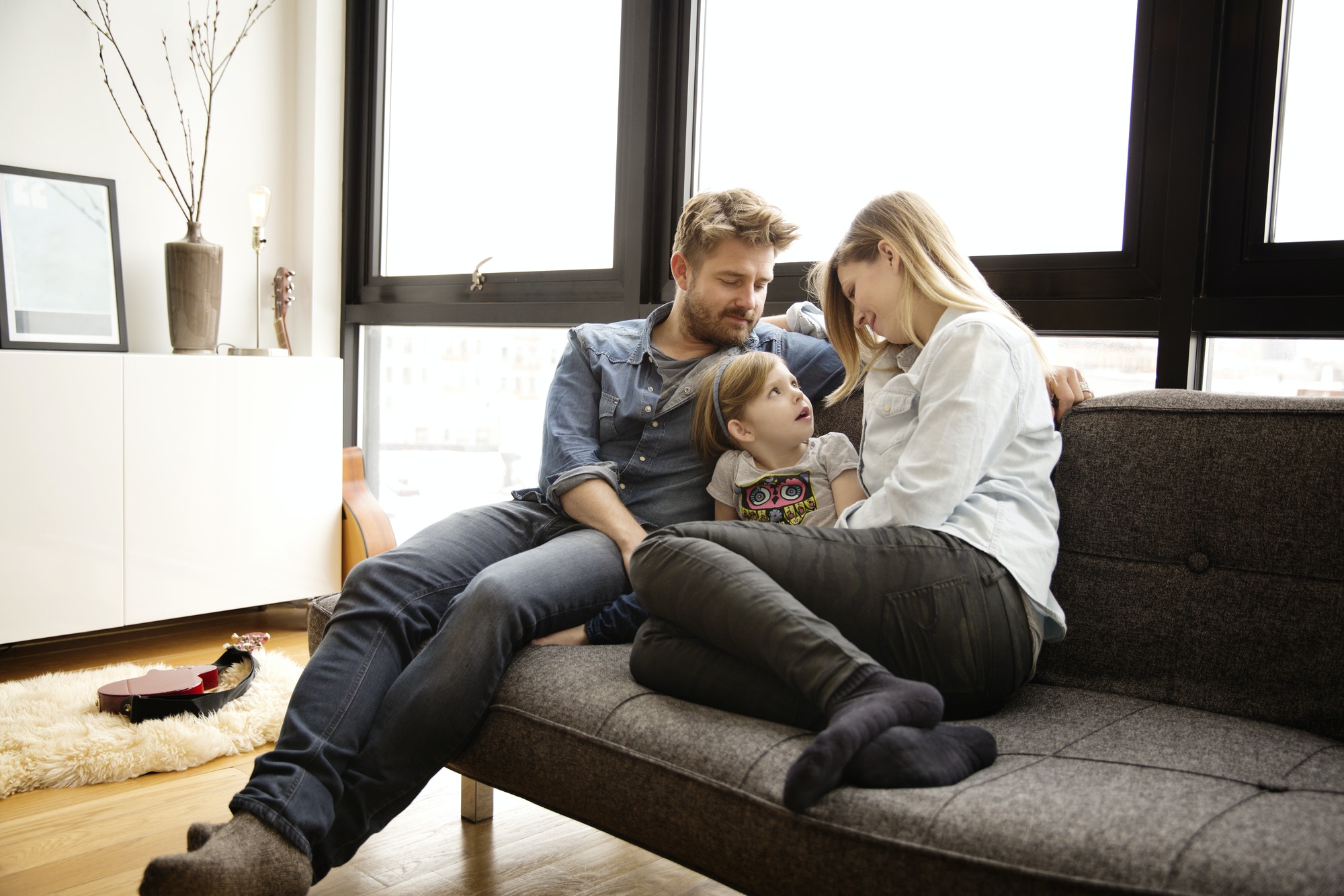 Family Sitting On Couch In Living Room
